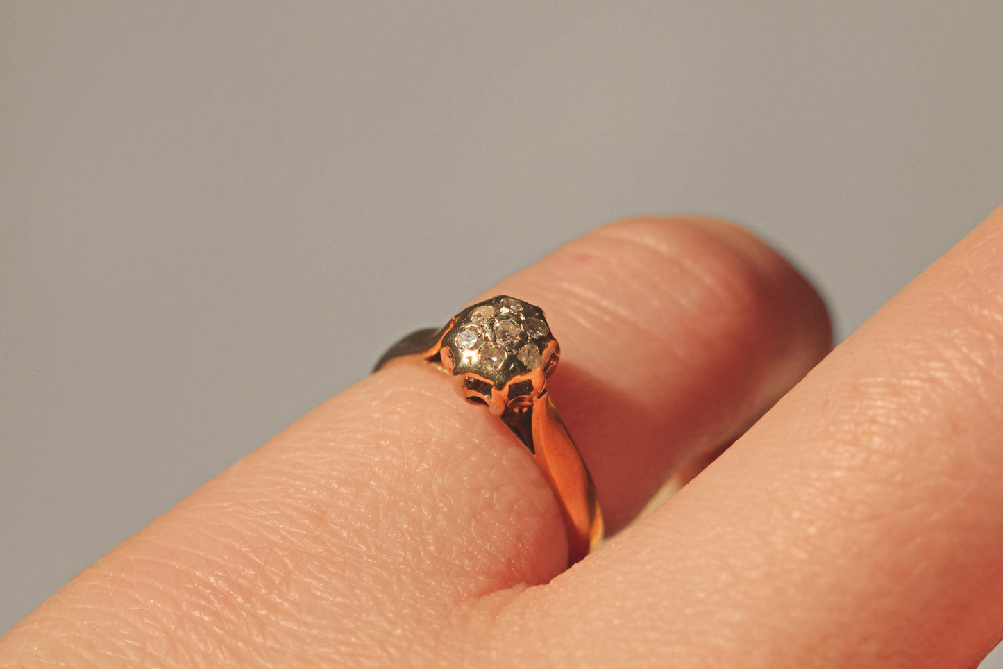 Side view of vintage diamond cluster ring showing raised gallery on finger