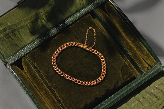 Antique gold curb bracelet resting inside a green velvet jewellery box