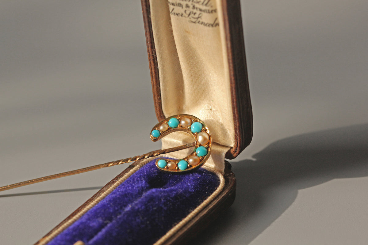 Antique 15ct lucky horseshoe pin, with turquoise and pearl stones displayed in an antique jewellery box