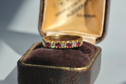 18ct gold ring with alternating diamonds and rubies, sparkling in the sun displayed on an antique jewellery box