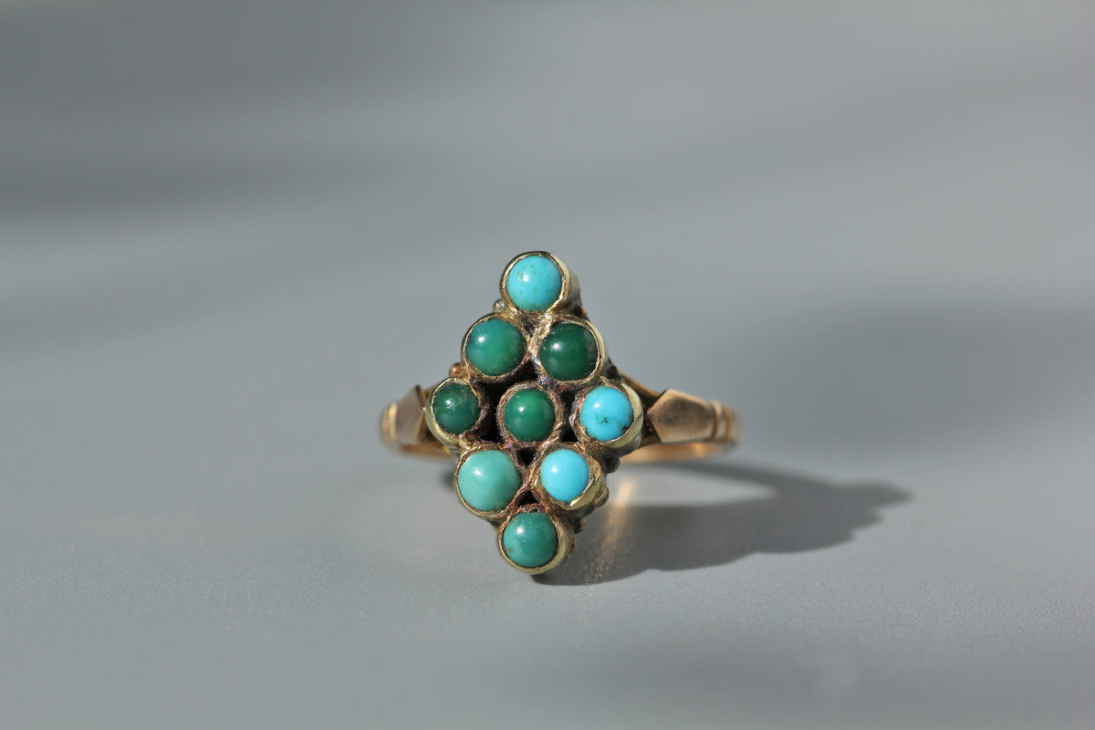 A 9ct gold antique ring featuring a cluster of round turquoise gemstones arranged in a geometric navette pattern, photographed on a neutral gray background.