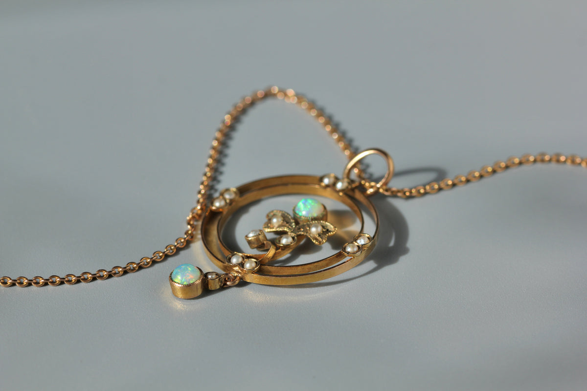Details of 9ct gold antique opal and pearl lavaliere pendant, on neutral grey background 