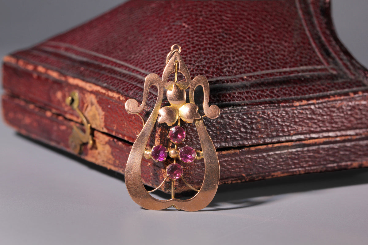 Antique Edwardian 9ct gold and pink tourmaline Art Nouveau pendant displayed on jewellery box

