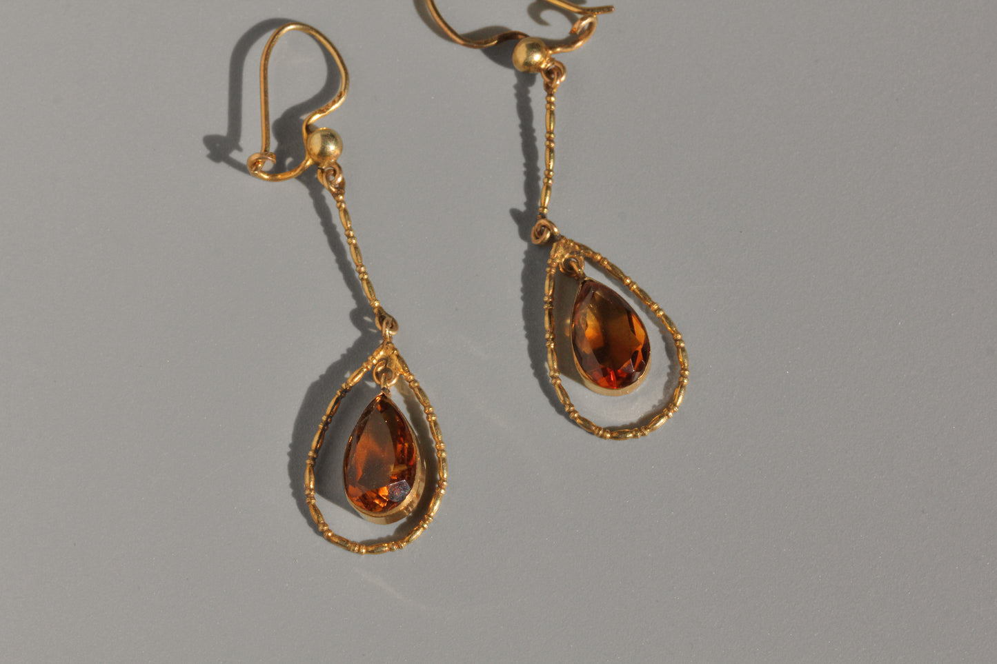 Close up of faceted topaz drop earrings in antique gold setting
