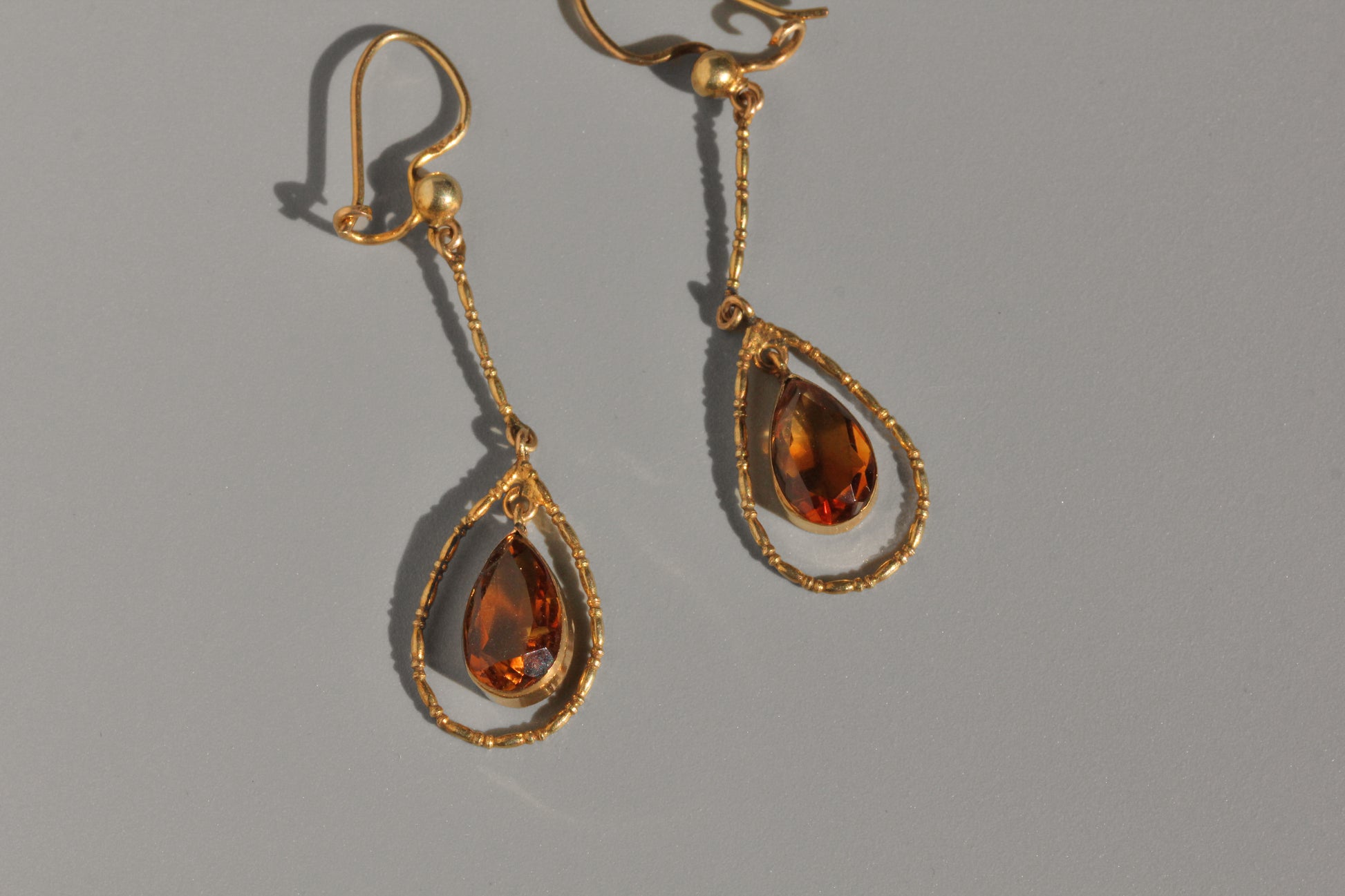 Close up of faceted topaz drop earrings in antique gold setting
