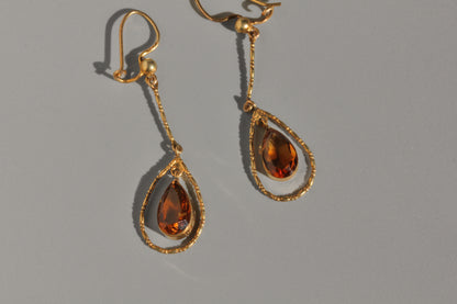 Close up of faceted topaz drop earrings in antique gold setting
