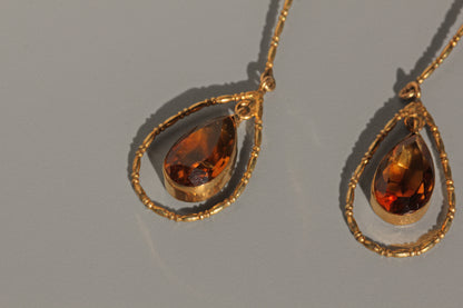 Detailed view of topaz gemstone in gold teardrop drop earrings