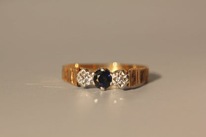 Close up of sapphire trilogy ring with bark textured shoulders
