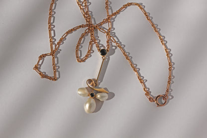 Close up of clover motif pearl and sapphire pendant in antique gold
