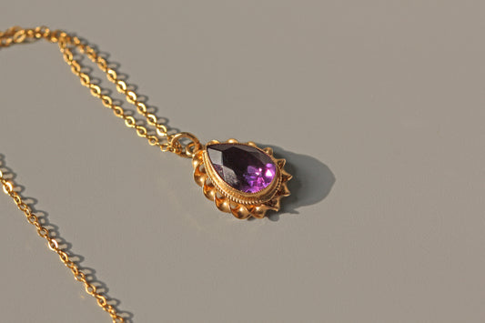 Close up of teardrop cut amethyst in gold bezel setting

