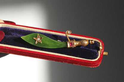 Antique scimitar brooch with green nephrite blade and ornate gold hilt
