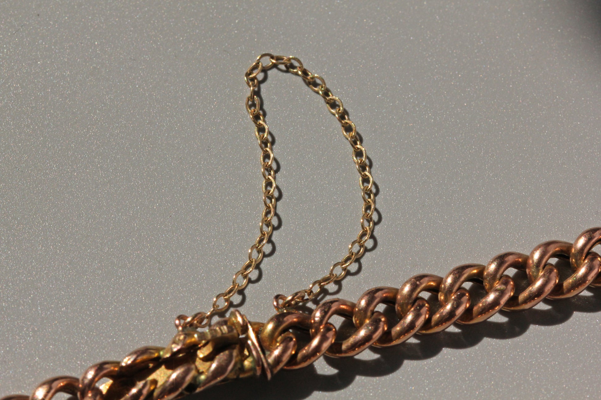 Antique rosy gold curb chain bracelet photographed in natural sunlight

