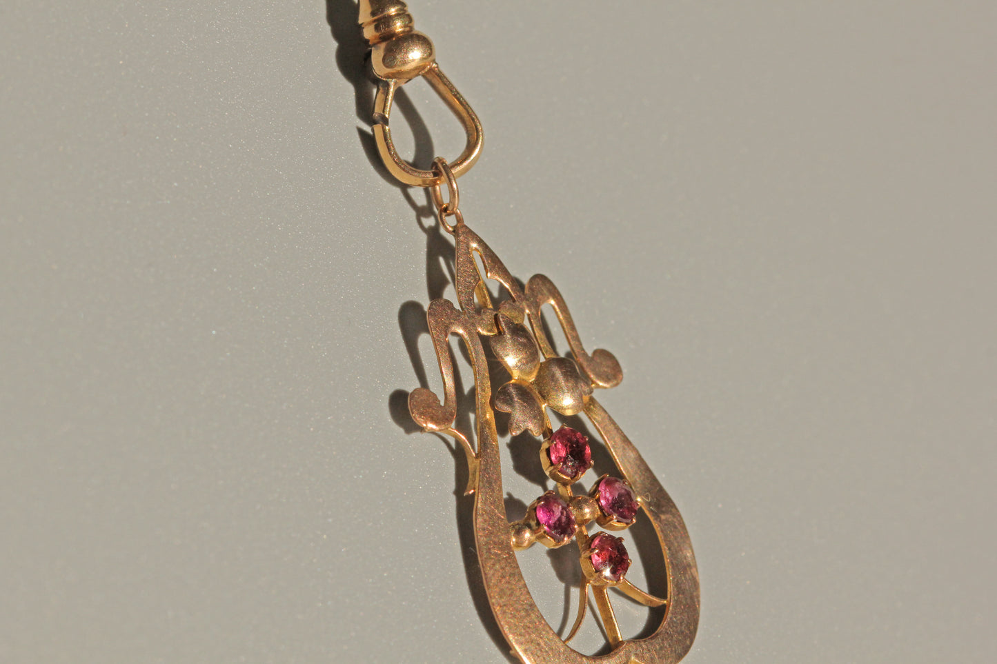 Close up of Art Nouveau ruby cluster pendant with openwork detail
