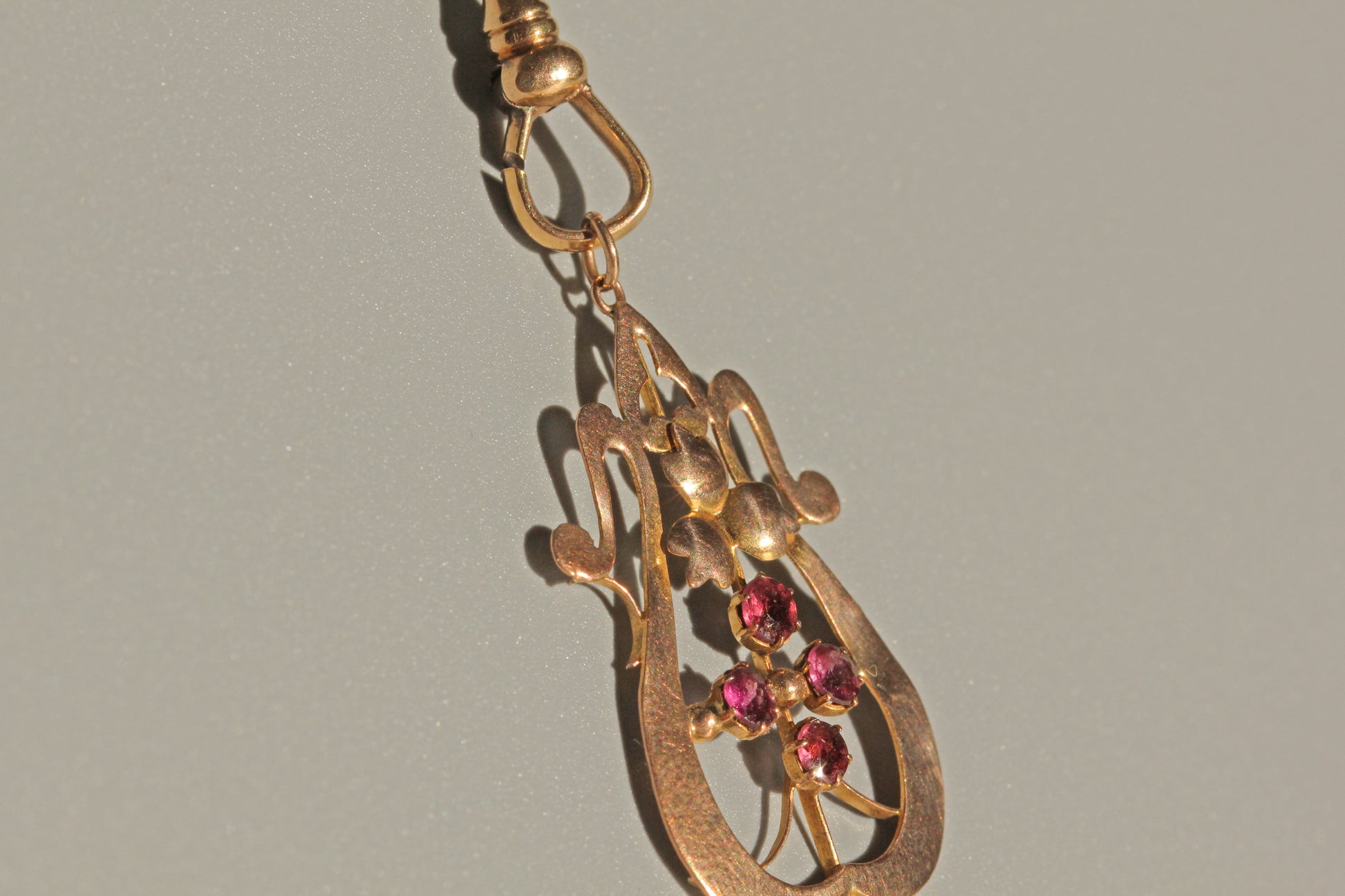 Close up of Art Nouveau ruby cluster pendant with openwork detail
