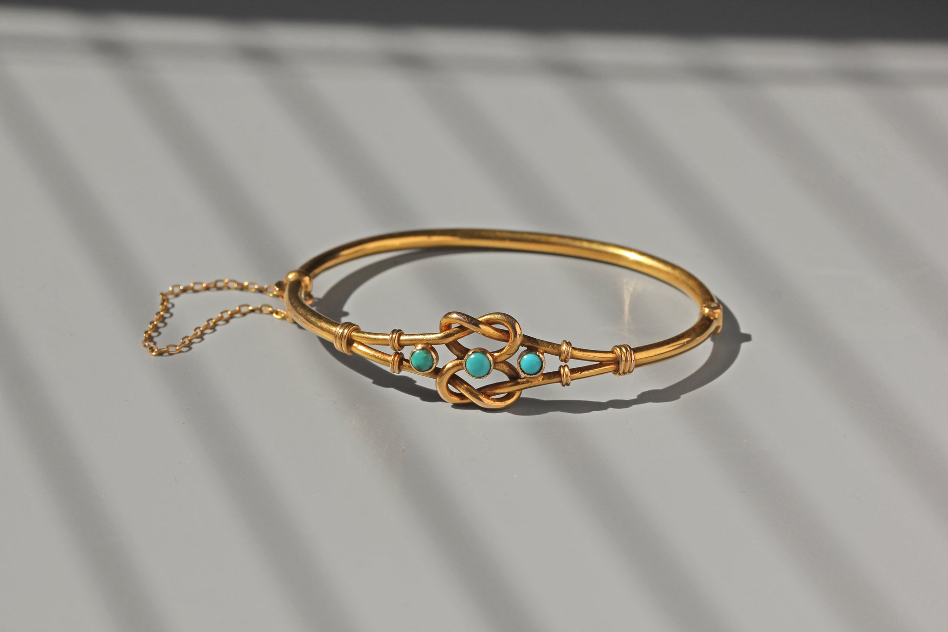 Antique gold bangle with turquoise and knot design
