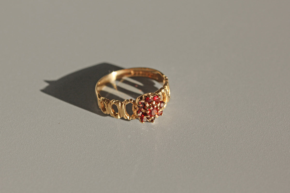 Close up of garnet daisy cluster ring with bark textured band
