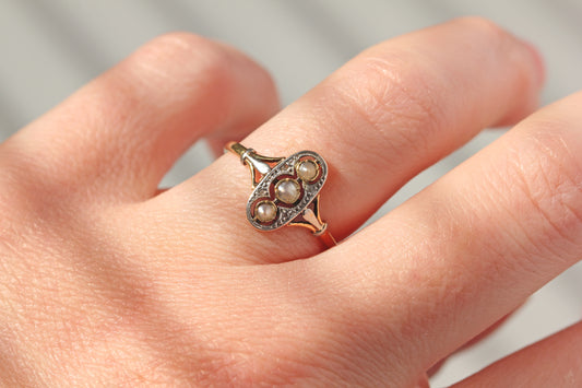 Edwardian navette ring with seed pearls and diamonds on hand
