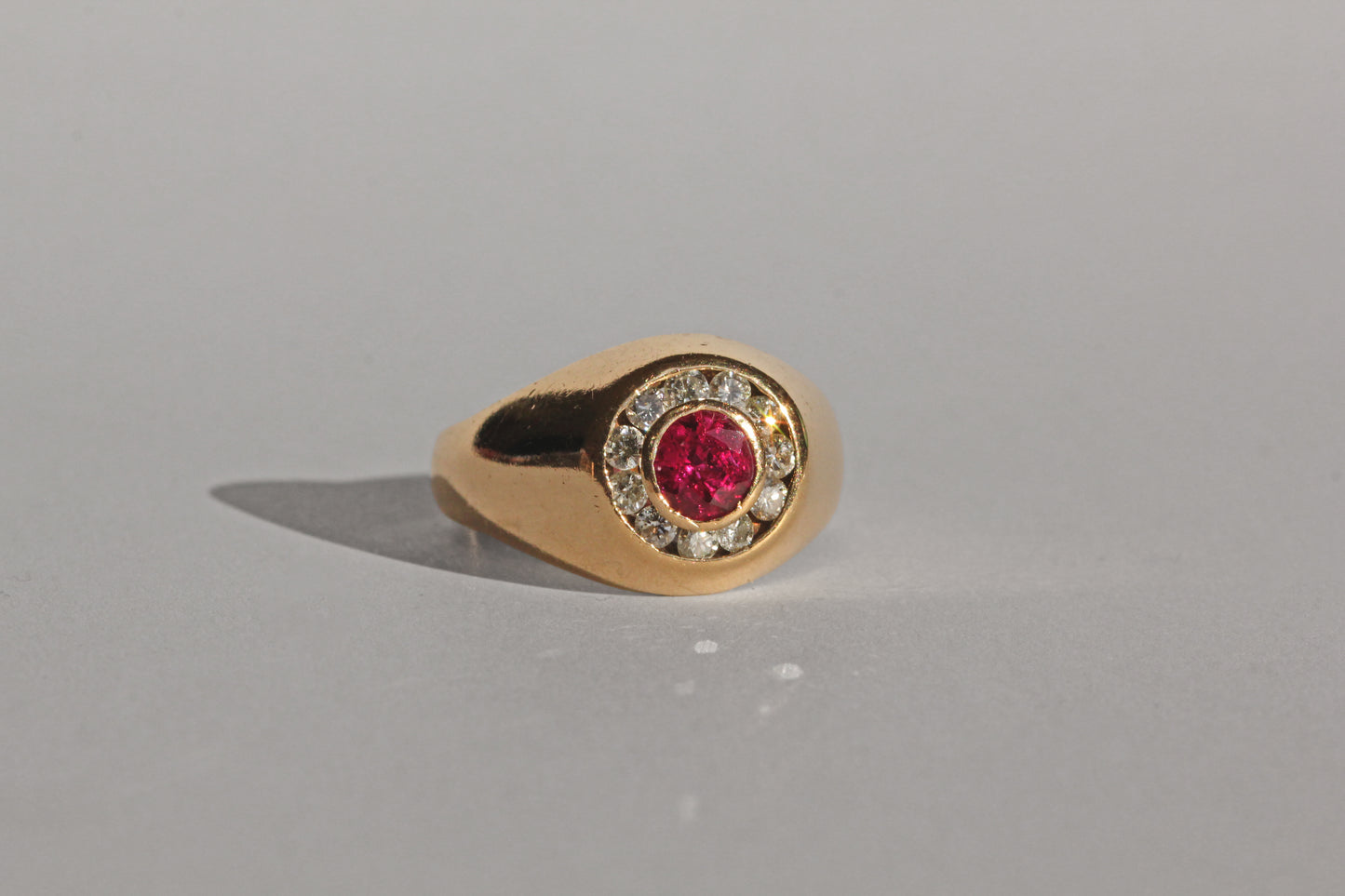 Chunky gold bombe ring with central ruby and diamond surround
