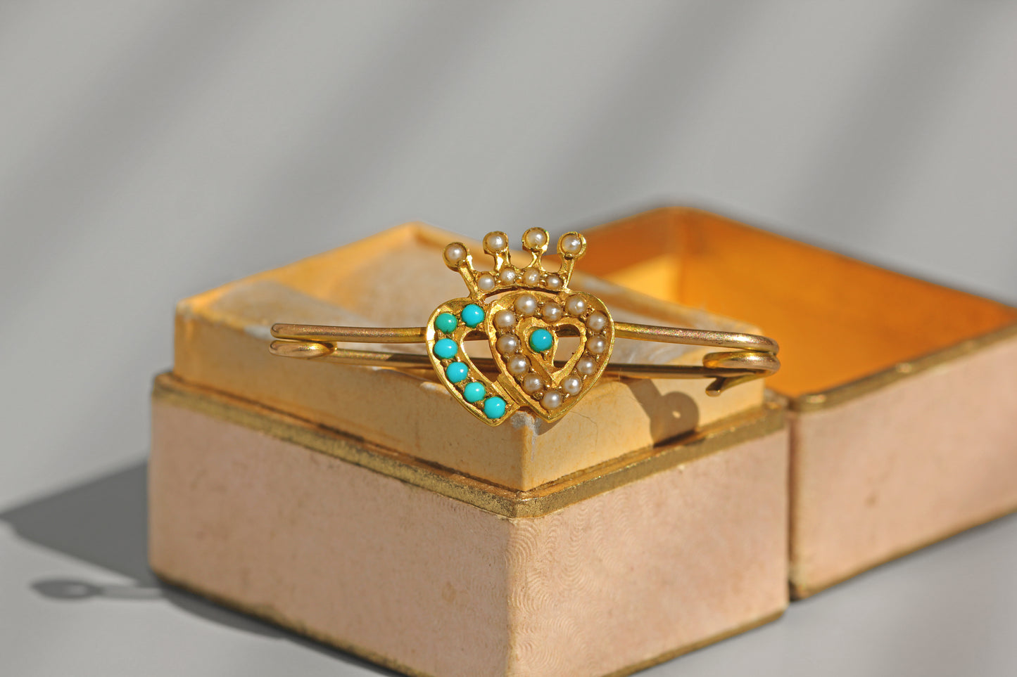 Antique gold Luckenbooth brooch photographed in natural sunlight showing turquoise and seed pearl detail
