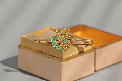 Antique gold Luckenbooth brooch photographed in natural sunlight showing turquoise and seed pearl detail
