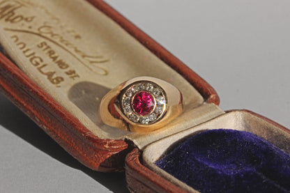 Mid century ruby ring with diamond halo and domed gold setting
