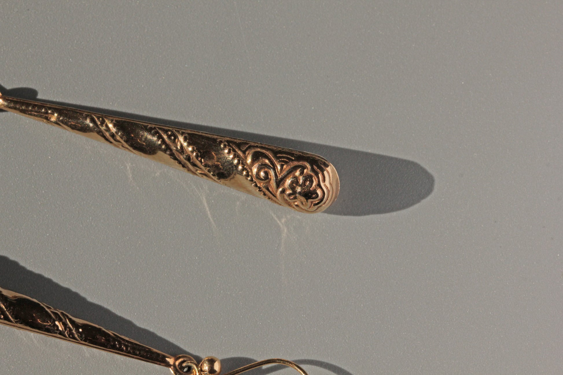 Close up of torpedo earrings with forget-me-not flower detail
