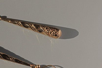 Close up of torpedo earrings with forget-me-not flower detail
