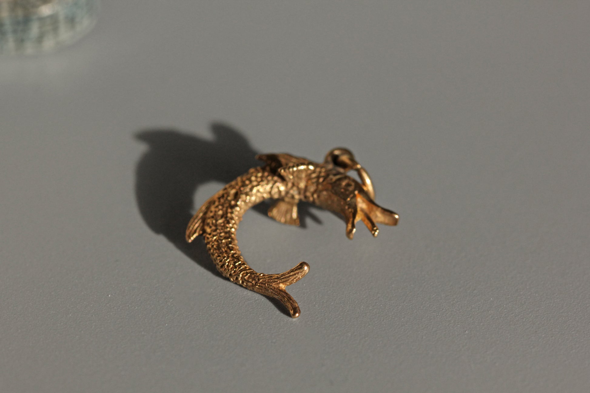 Side view of pike fish charm showing curved body
