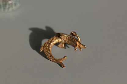 Side view of pike fish charm showing curved body
