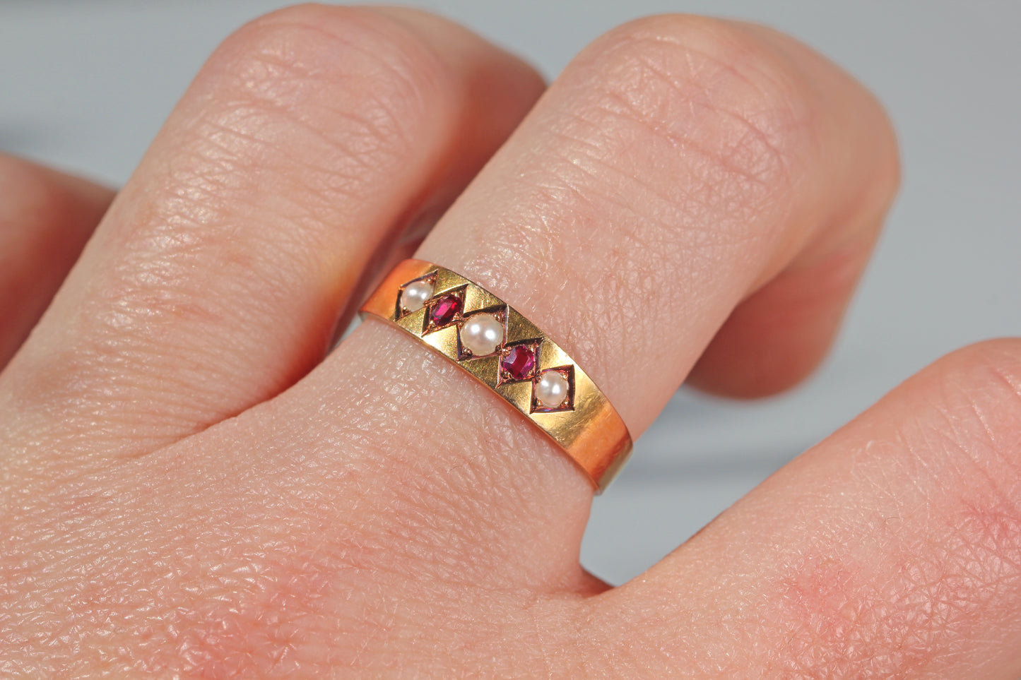 Antique ruby and pearl ring in 18 carat gold worn on hand
