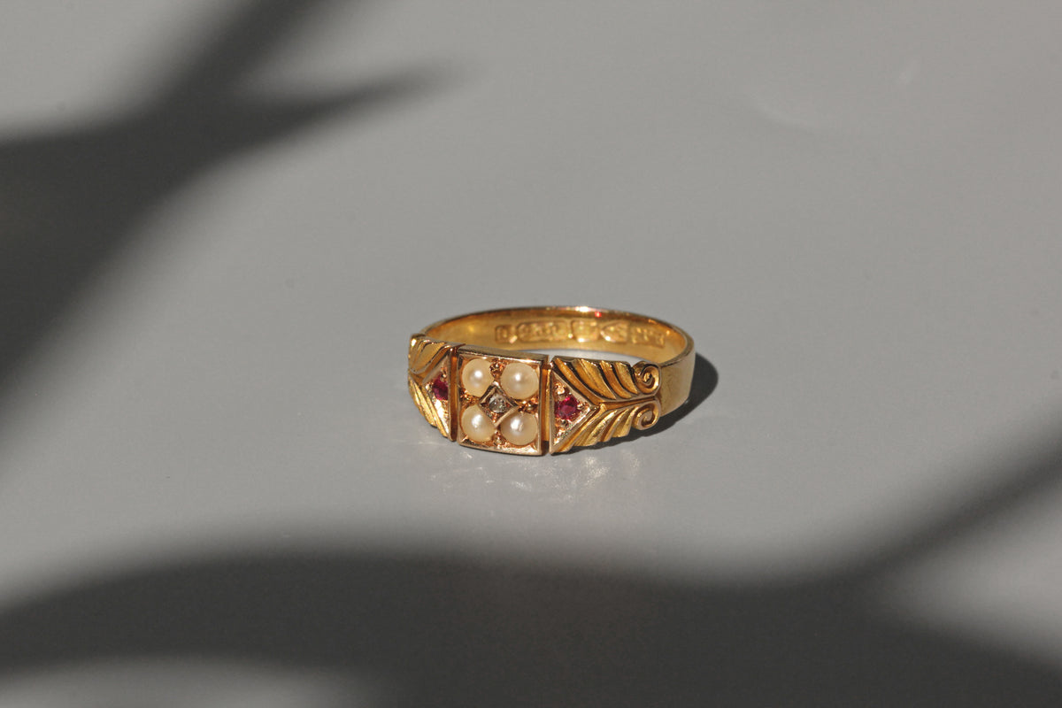 Gold ring with pearls and a ruby on a gray background