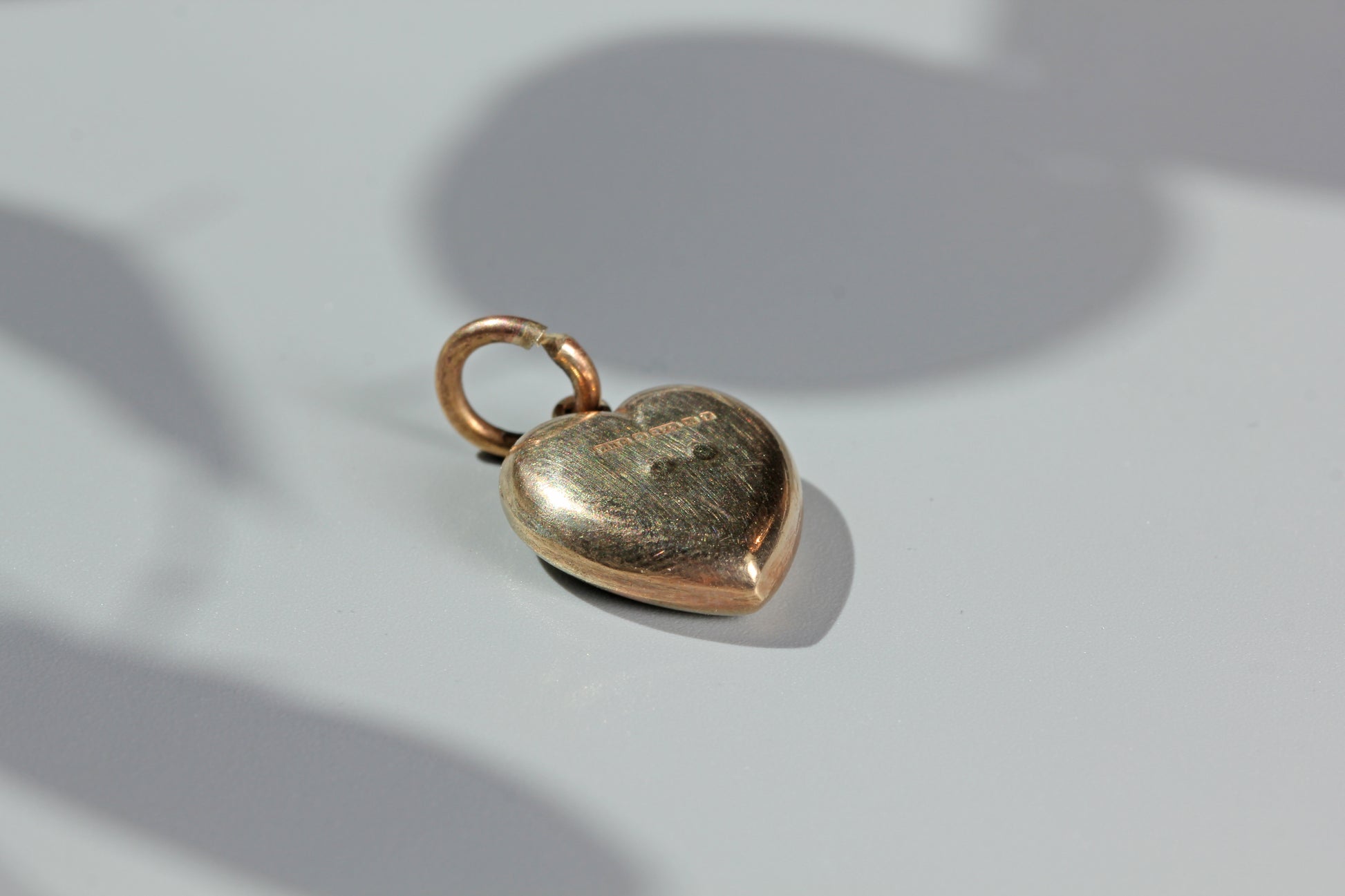 Heart-shaped gold charm on a light gray background