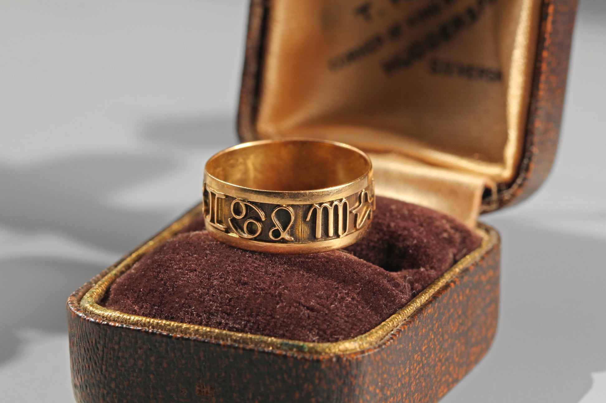 Vintage zodiac ring resting inside an antique velvet jewellery box

