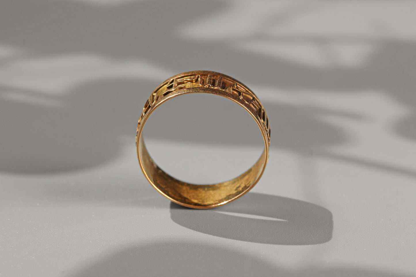 Vintage astrology themed gold band ring photographed in natural sunlight
