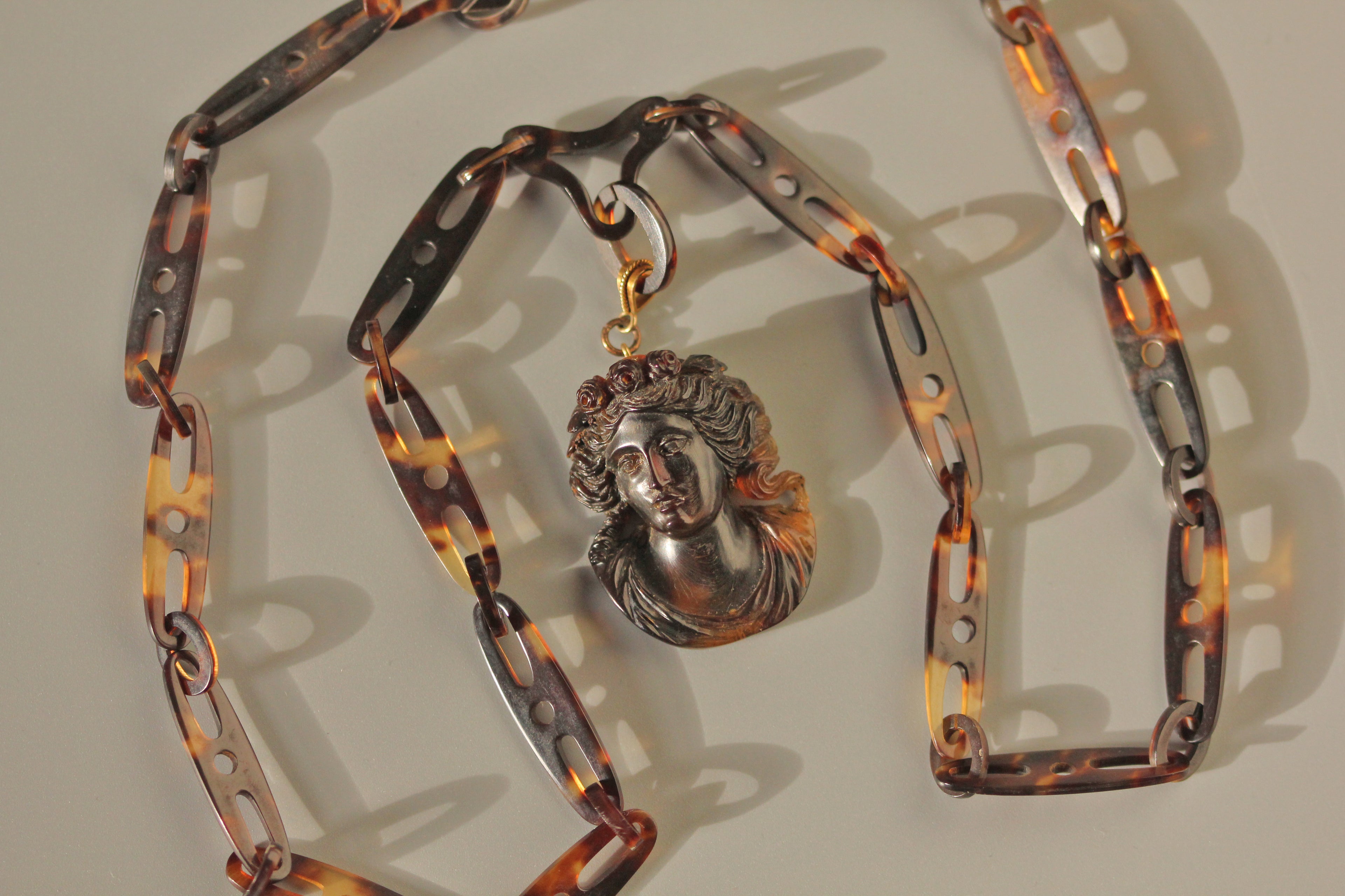 Antique pendant necklace with a sculpted classical face, suspended from a tortoiseshell chain