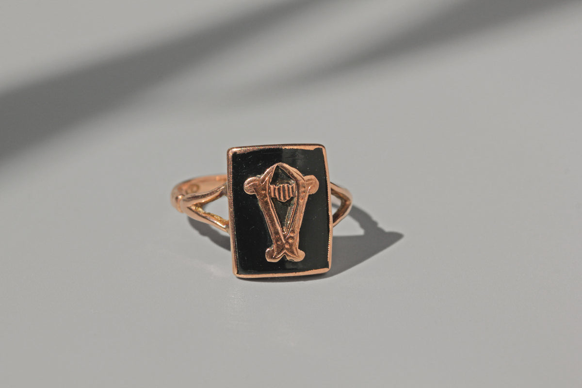 Ring with a black stone and gold design on a gray background