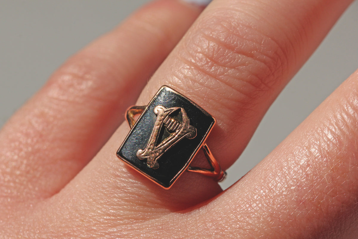 Edwardian antique onyx lyre ring in 9ct rose gold on ring finger