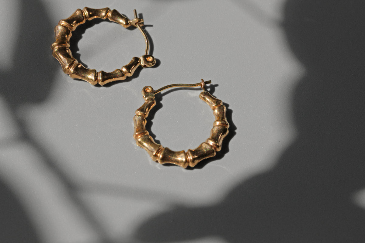 Close up of gold bamboo hoop earrings with hinged closure
