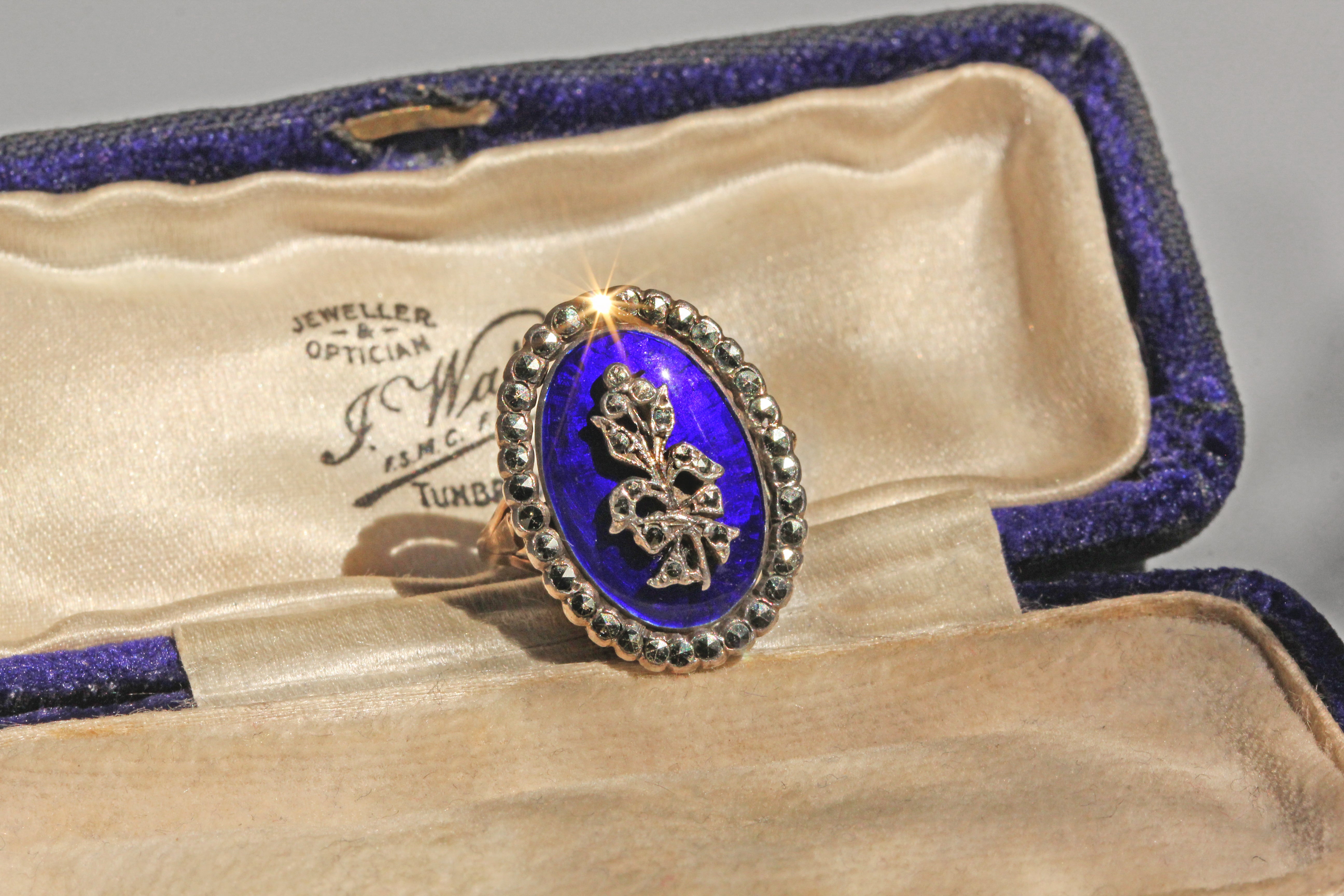 Vintage ring with blue enamel and gold accents in an open jewelry box.
