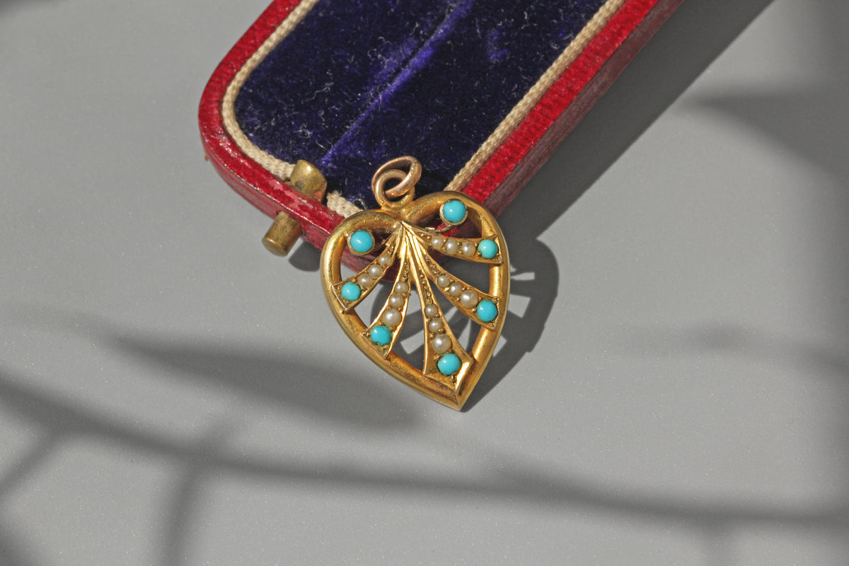 Antique gold heart shaped pendant with turquoise stones on a red and blue velvet box