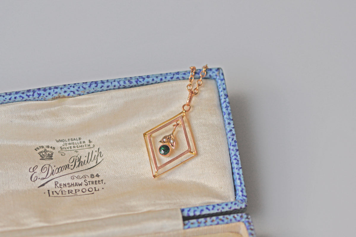 Close up of green tourmaline and seed pearl floral pendant
