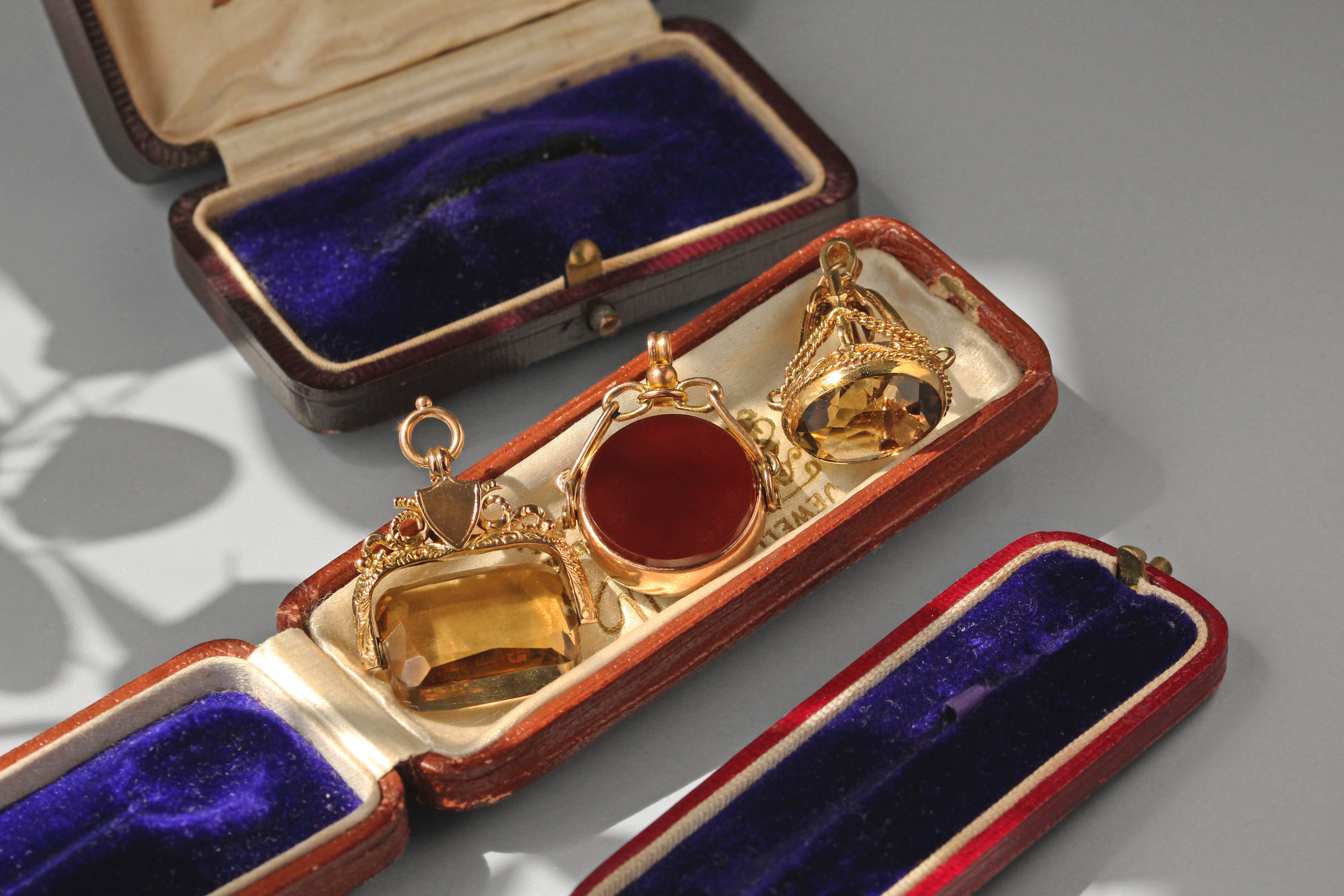 Gold jewelry set with red stone in a velvet-lined box on a gray background