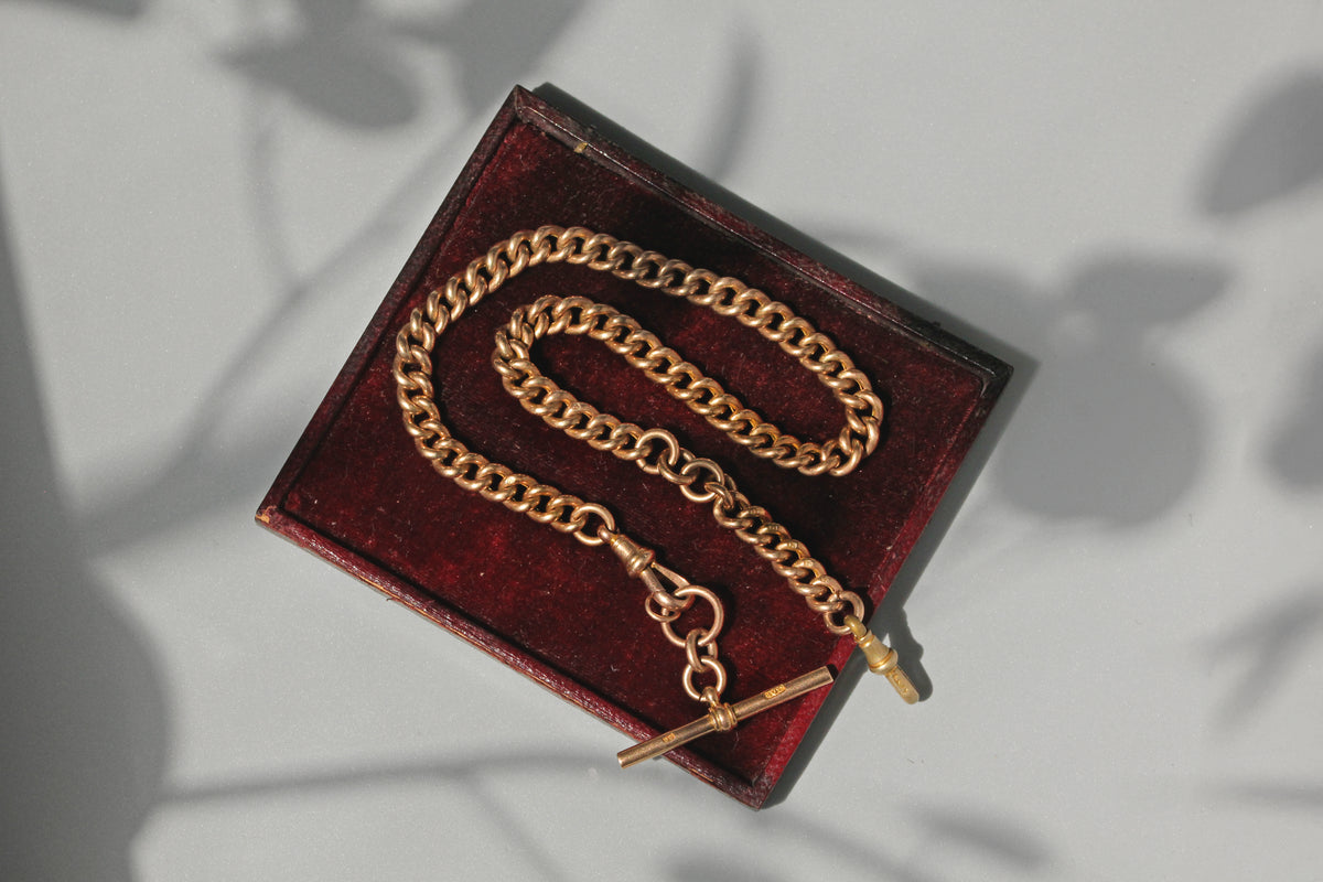 Antique curb link Albert chain with T-bar in 9 carat gold on red jewellery box