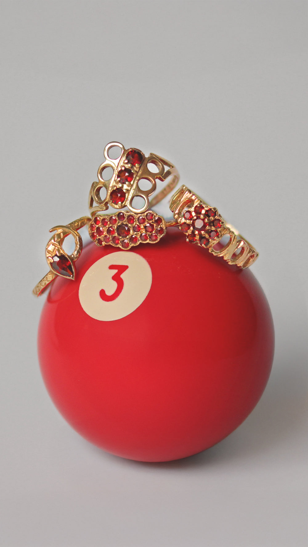 Red snooker ball with vintage gold rings featuring garnet stones