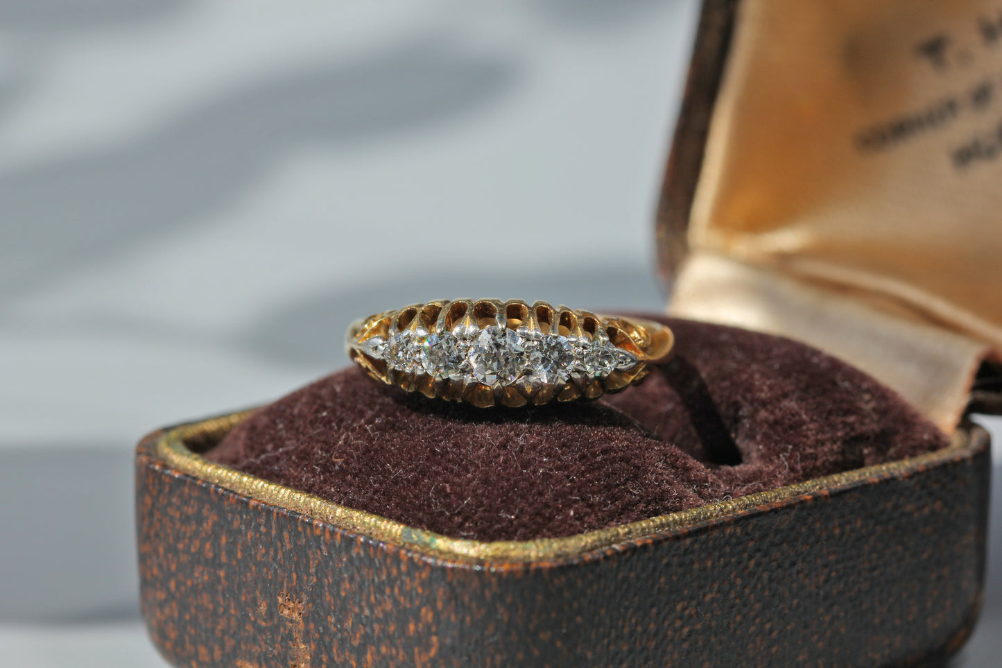 Antique 18ct gold five stone diamond ring displayed on antique jewellery box
