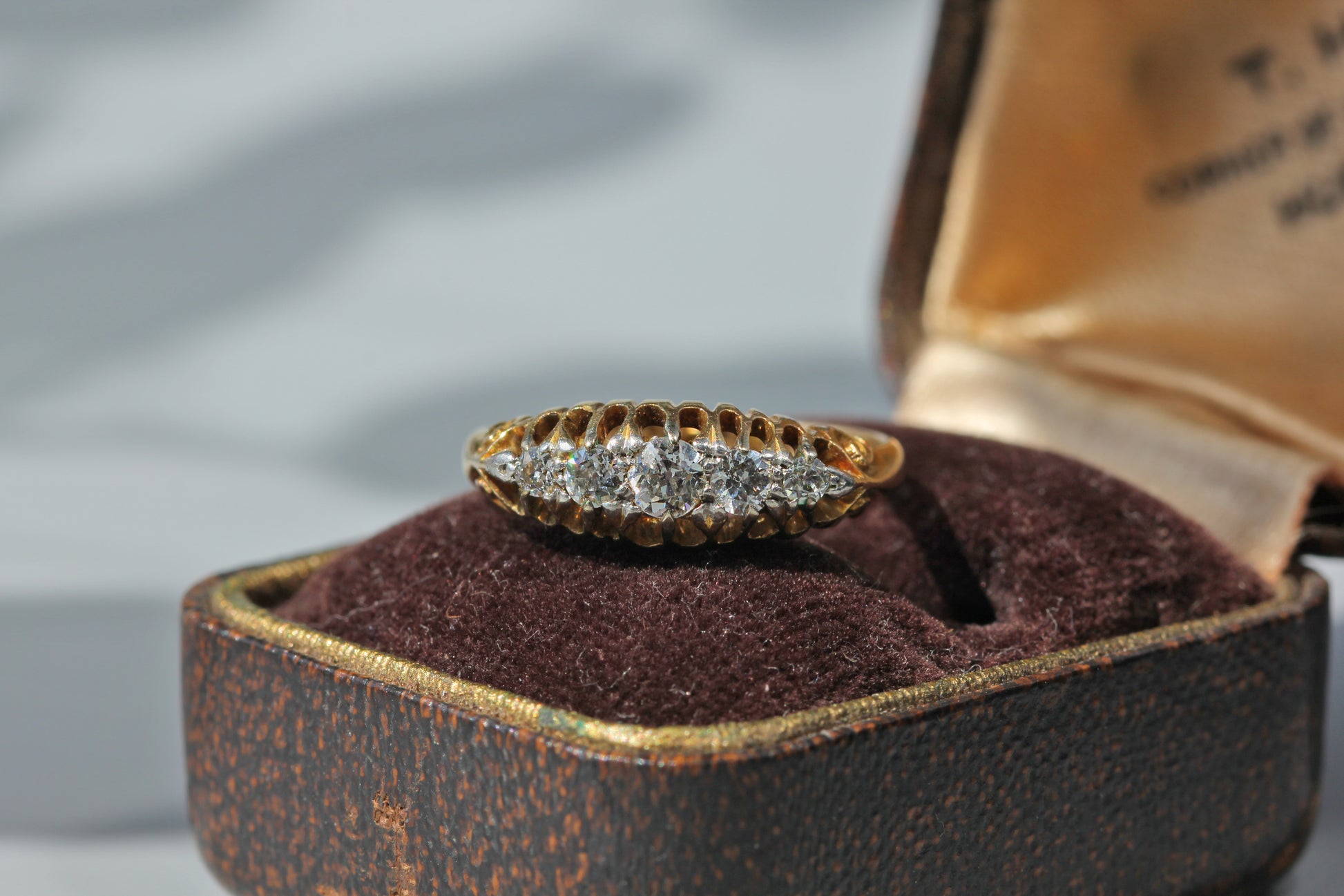 Antique 18ct gold five stone diamond ring displayed on antique jewellery box