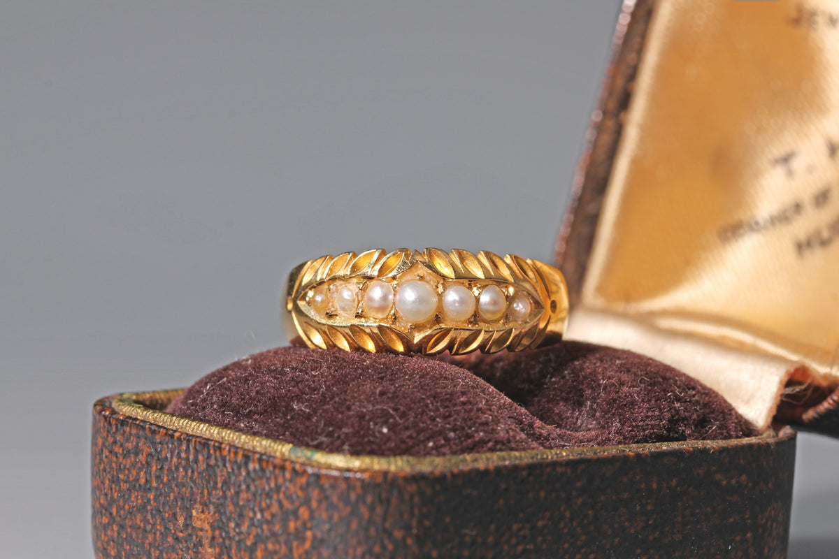 Antique 18ct gold pearl ring displayed on antique jewellery box