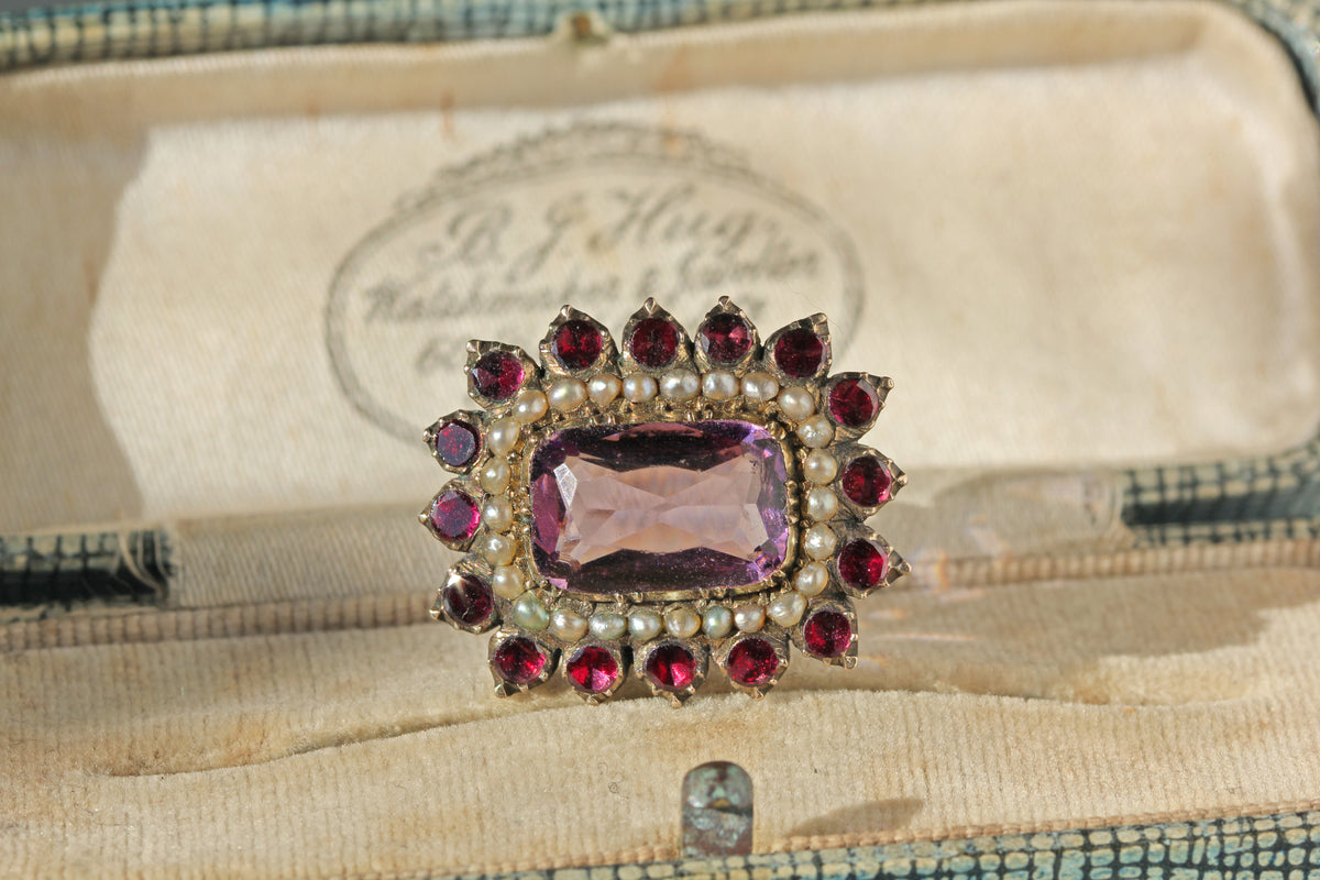 Antique 9ct gold Georgian brooch with amethyst, garnets and pearls in collet settings with closed backs displayed on antique jewellery box