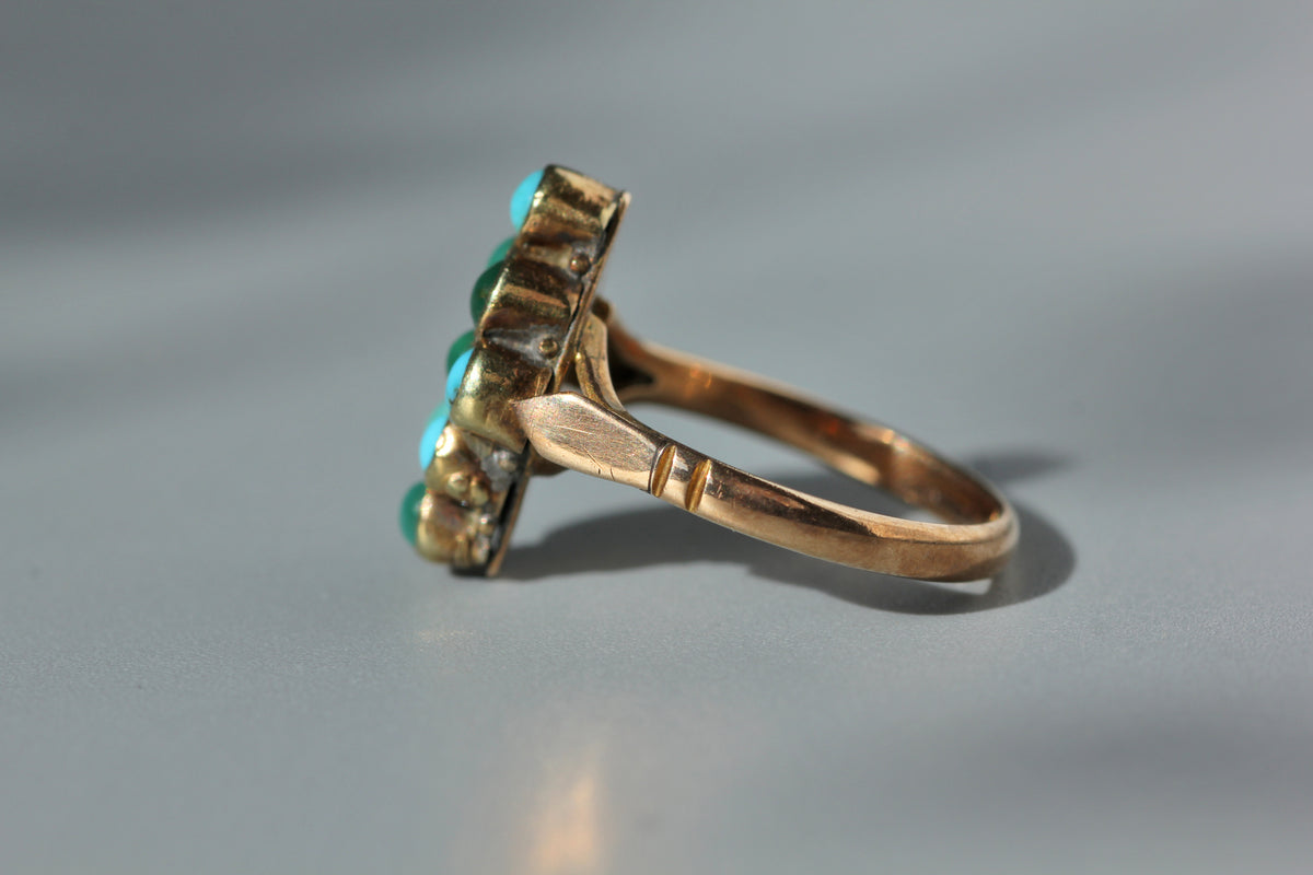 Side view of spade shoulder details on antique 9ct gold ring displayed on grey background