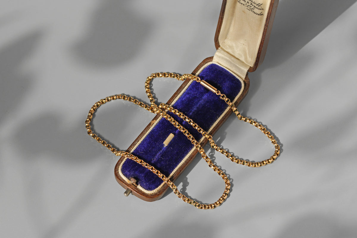 An antique 9ct yellow gold chain with a barrel clasp, displayed on an antique jewellery box